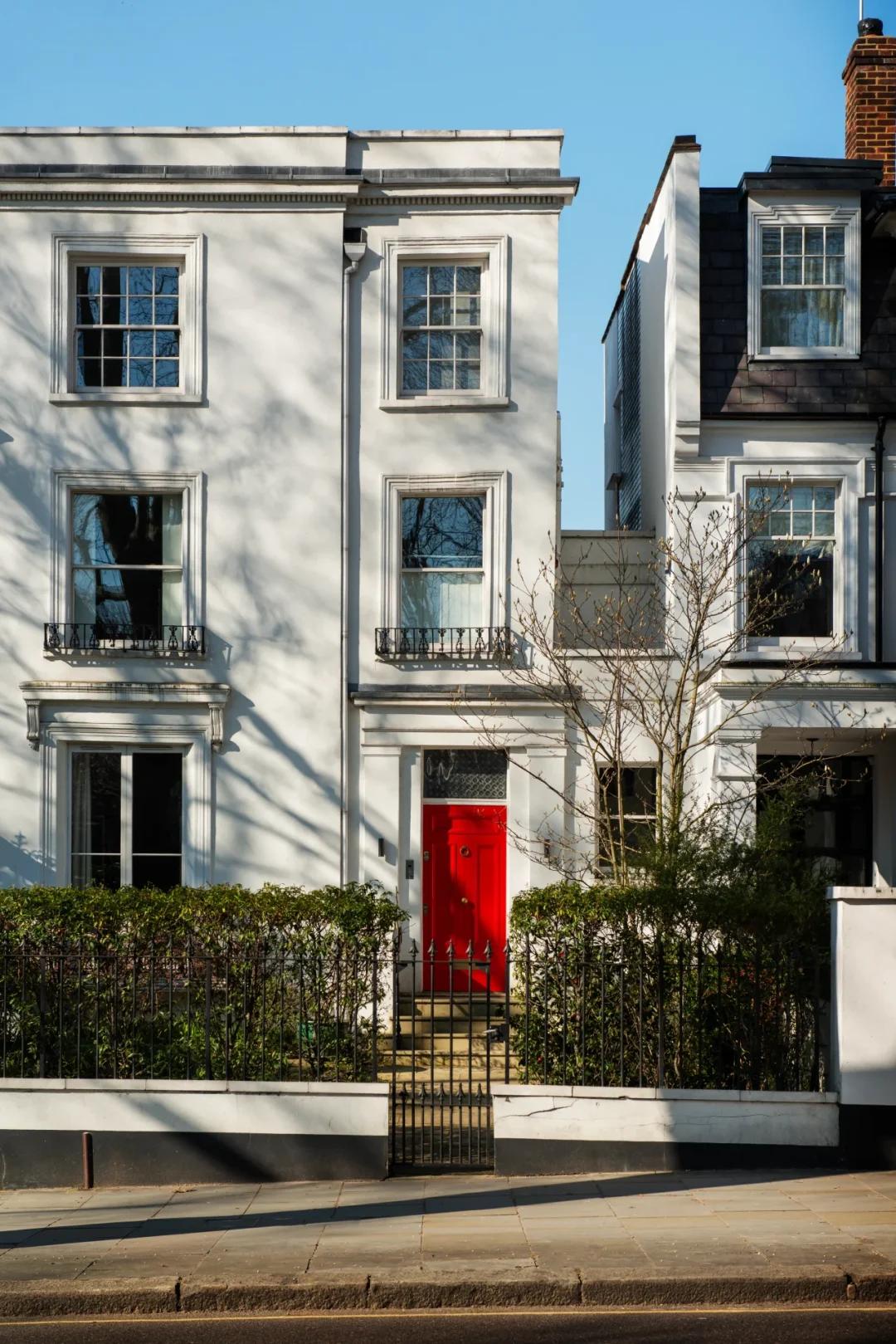 Townhouse mit weißer Fassade und roter Eingangstür in urbaner Lage