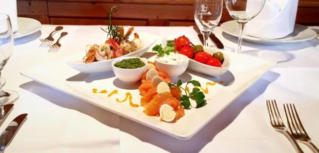 Fein angerichtete Vorspeisenplatte im Wellnesshotel Tirol Isserwirt mit Lachs, Garnelen, frischen Tomaten und hausgemachten Dips in stilvollem Restaurantambiente
