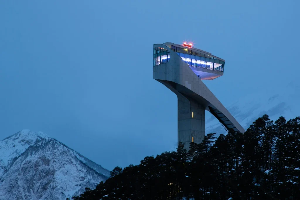 Bergiselschanze in Innsbruck bei D&auml;mmerung nahe dem Wellnesshotel Tirol Isserwirt mit markanter moderner Architektur vor alpiner Winterkulisse
