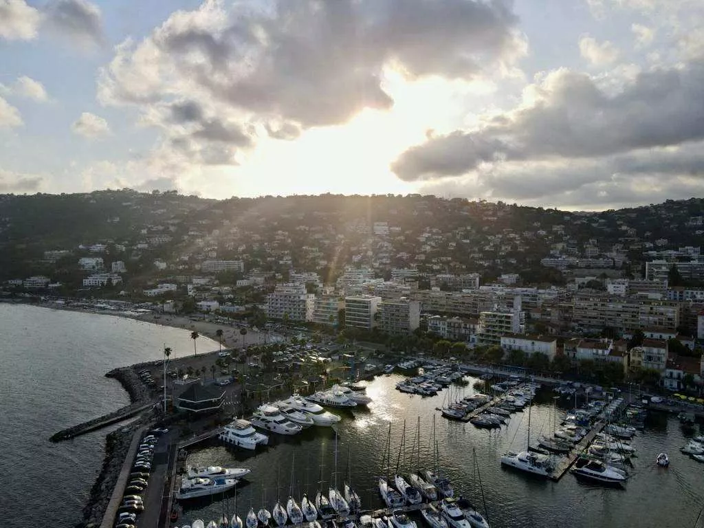 Hafen voller Luxusyachten und Segelboote an der Mittelmeerküste bei Sonnenuntergang, beliebter Aufenthaltsort deutscher Milliardäre