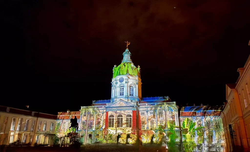 Illuminiertes Schloss Charlottenburg bei Nacht während des Festival of Lights Berlin 2025 mit farbenfroher Projektion auf der Fassade.