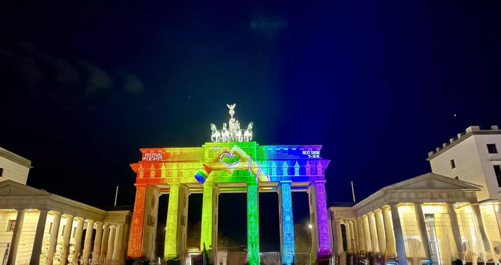 Illuminiertes Brandenburger Tor bei Nacht während des Festival of Lights Berlin 2025 mit bunter Projektion in Regenbogenfarben.