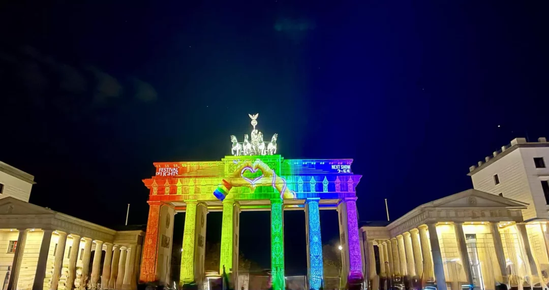 Illuminiertes Brandenburger Tor bei Nacht während des Festival of Lights Berlin 2025 mit bunter Projektion in Regenbogenfarben.