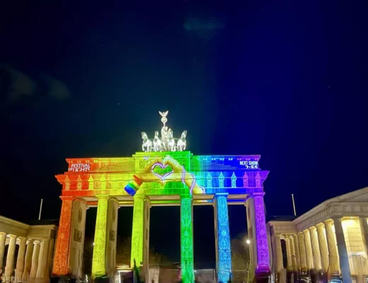 Illuminiertes Brandenburger Tor bei Nacht während des Festival of Lights Berlin 2025 mit bunter Projektion in Regenbogenfarben.
