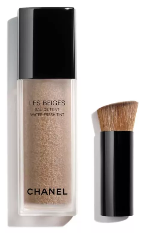 Teuerste Make-up-Marke der Welt – Chanel Les Beiges Eau de Teint im transparenten Flakon mit Mikro-Pigmenten, daneben ein kurzer Auftragspinsel.