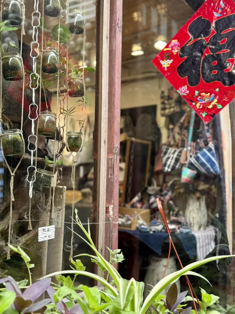 China Reise - Traditionelles Schaufenster in Shanghai mit chinesischem Glückssymbol, hängenden Pflanzen und handgefertigten Produkten