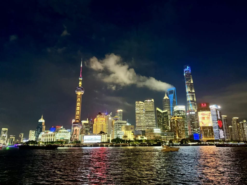 China Reise - Nachtaufnahme von The Bund in Shanghai mit beleuchteter Skyline und Huangpu-Fluss im Vordergrund