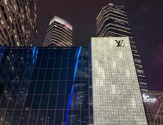 China Reise -Beleuchteter Louis Vuitton Store in Shanghai bei Nacht mit modernen Hochhäusern im Hintergrund