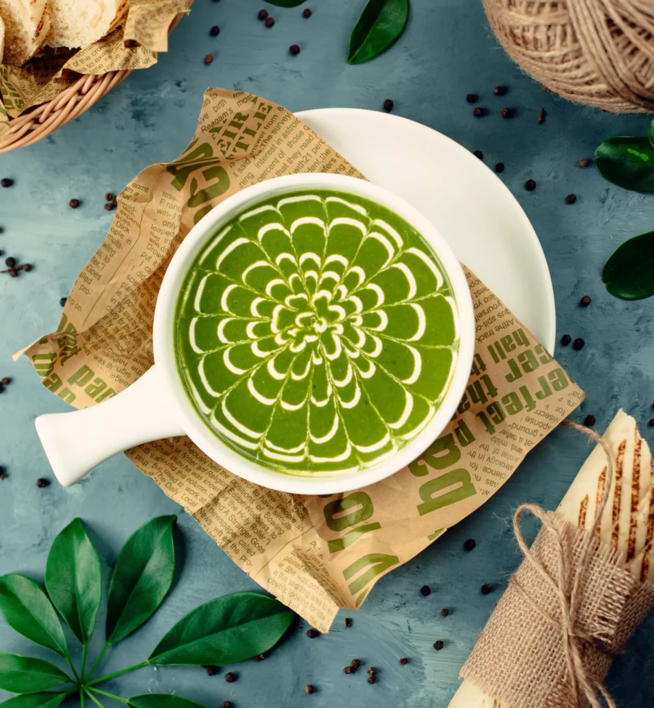 Matcha Latte mit aufwendiger weißer Latte-Art in Blumenform, von oben fotografiert.