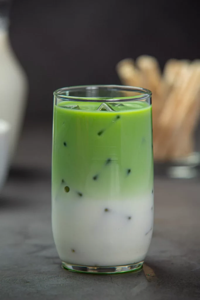 Geschichteter Iced Matcha Latte in hohem Glas mit Eiswürfeln – grün oben, weiße Milch unten.
