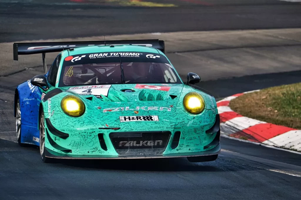 Grün-blauer Porsche 911 GT-2 RS mit gelben Scheinwerfern auf der Nürburgring-Nordschleife in einer schnellen Kurve.