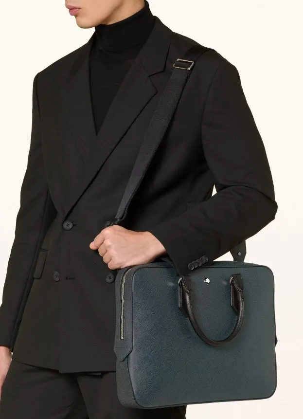 Mann im schwarzen Anzug mit schwarzem Rollkragen trägt eine dunkelgrüne Business-Aktentasche mit Schulterriemen.