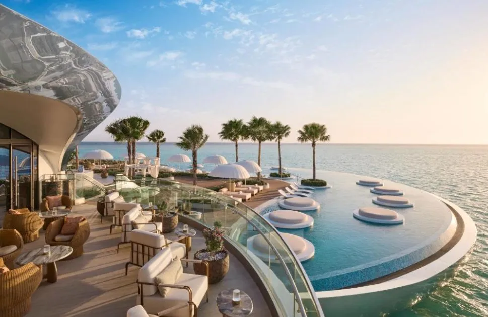 Panoramaterrasse im Shebara Resort mit Lounge-Möbeln, Glasbrüstung und kreisförmigem Infinity-Pool mit Insel-Loungern direkt über dem Roten Meer bei goldenem Abendlicht.