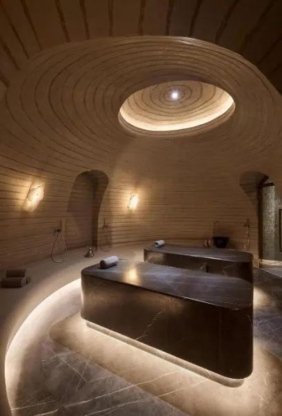 Hammam im Shebara Resort mit zwei dunklen Steintischen, ringförmig gerippter Kuppel und zenitalem Oberlicht in warmem, indirektem Licht.