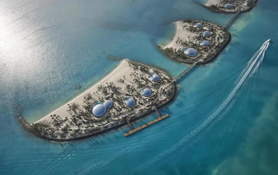 Luftaufnahme mehrerer Sandinseln von Shebara Island mit palmenbewachsenen Stränden, futuristischen Kuppelbauten und Stegen im türkisblauen Roten Meer; Schnellboot zieht weiße Spur.