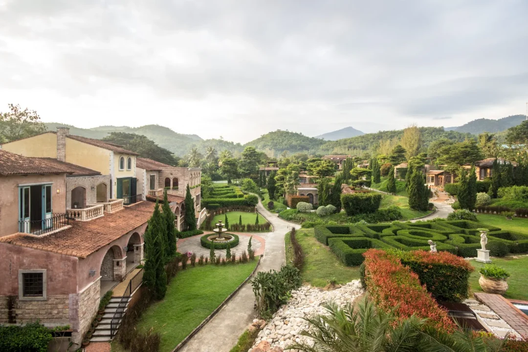 Exklusive Immobilien in Italien – mediterrane Villa im italienischen Stil mit formalem Garten, Zypressen und Blick auf grüne Hügellandschaft.