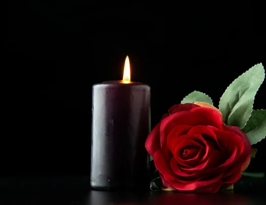 Diane Keaton ist Tod – schwarze Trauerkerze mit roter Rose vor schwarzem Hintergrund