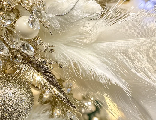 Luxuriöse Adventsdekoration mit weißen Federn, goldenen Ornamenten und funkelnden Kristallanhängern.