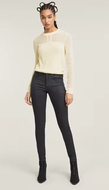 Model trägt graue Skinny Jeans und cremefarbenen Feinstrickpullover – moderner Winterlook 2025 mit Stiefeletten