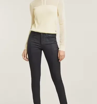 Model trägt graue Skinny Jeans und cremefarbenen Feinstrickpullover – moderner Winterlook 2025 mit Stiefeletten