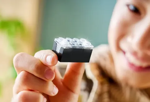Kind hält einen LEGO Smart Stein mit transparenter Oberfläche zwischen den Fingern