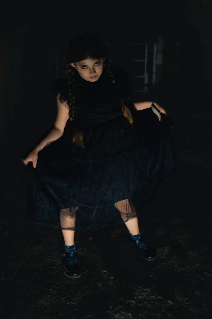 Dunkles Kinder-Faschingskostüm mit schwarzem Tüllkleid und geflochtenen Zöpfen – stimmungsvolle Inszenierung mit geheimnisvoller Atmosphäre