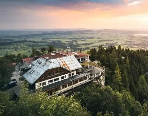 Blaue Burg Boutiquehotel auf dem Falkenstein in Pfronten mit Panoramablick über das Allgäu bei Sonnenuntergang