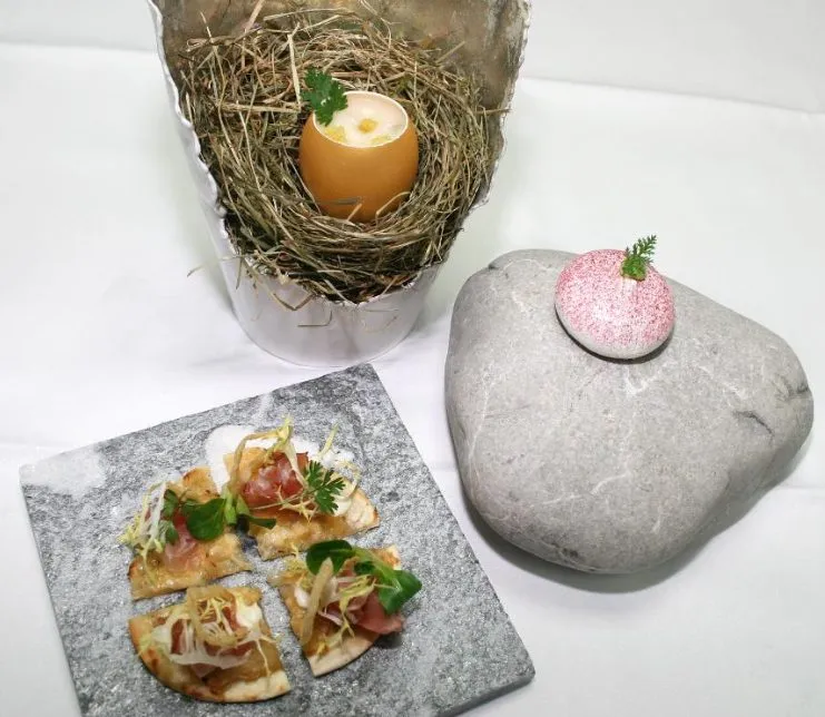 Fine-Dining-Fingerfood aus der Blauen Burg mit kunstvoll angerichteten Häppchen auf Steinplatte und Dessert im Ei serviert