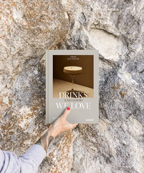 Drinks And Food We Love Rezeptbuch von Simon Schlachter vor Natursteinwand gehalten – alkoholfreie Drinks und Fingerfood aus der Blauen Burg