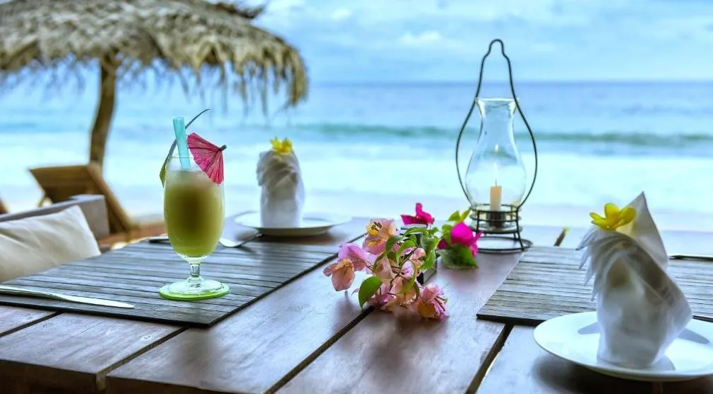 Romantisches Dinner am Strand in Sri Lanka mit tropischem Cocktail und Meerblick w&auml;hrend luxuri&ouml;ser Flitterwochen
