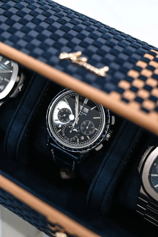 Luxusuhr in einer dunklen Uhrenbox mit blauem, gewebtem Deckel.