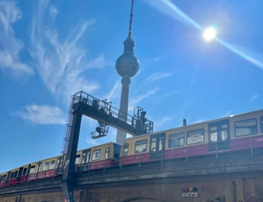 Rote U-Bahn, alte Stadtbahnbögen und der Fernsehturm im Hintergrund: Kaum ein Motiv zeigt Berlins Mischung aus rauem Alltag und großer Kulisse so direkt.