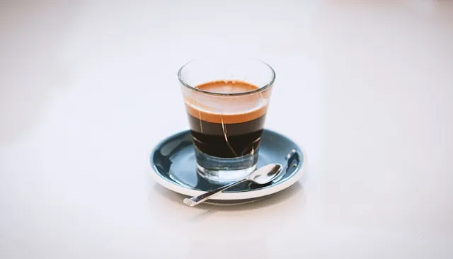 Espresso im Glas mit goldbrauner Crema auf einer Untertasse