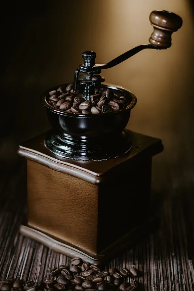 Manuelle Kaffeemühle aus Holz mit gerösteten Kaffeebohnen
