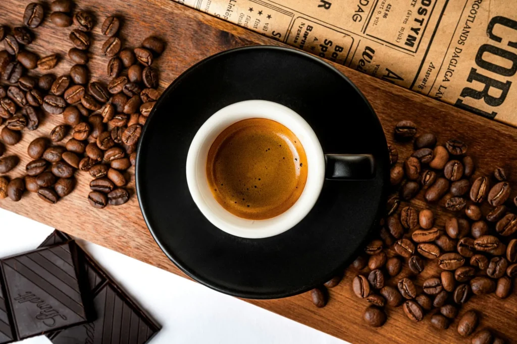 Espresso mit goldbrauner Crema neben gerösteten Kaffeebohnen