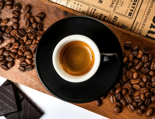 Espresso mit goldbrauner Crema neben gerösteten Kaffeebohnen