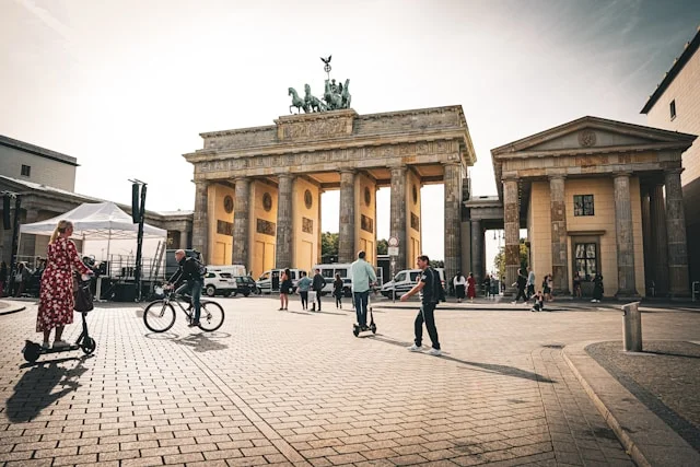 Brandenburger Tor in Berlin mit Radfahrern, E-Scootern und Passanten auf dem Pariser Platz