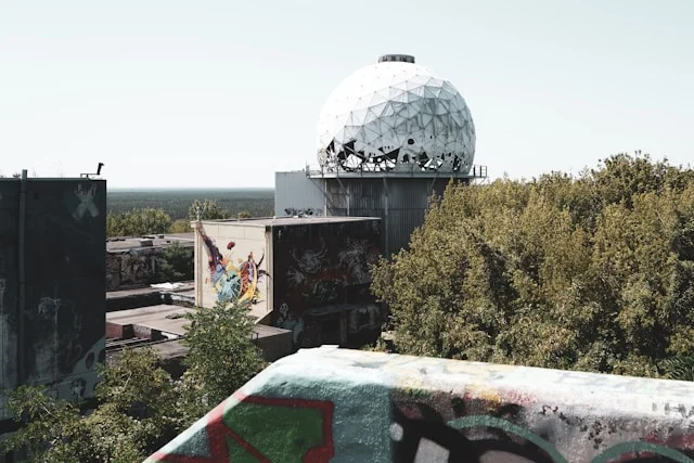 Weiße Radarkuppel der ehemaligen Abhörstation auf dem Berliner Teufelsberg mit Graffiti und Bäumen