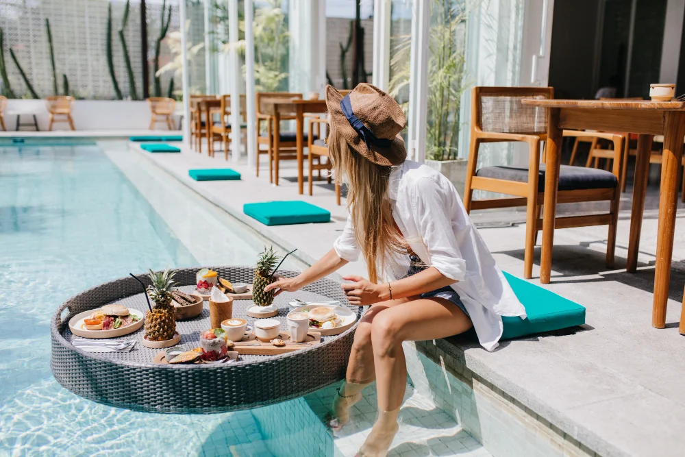 Frau genießt gesundes Frühstück am Pool eines Wellnesshotels als Symbol für Longevity und regeneratives Reisen