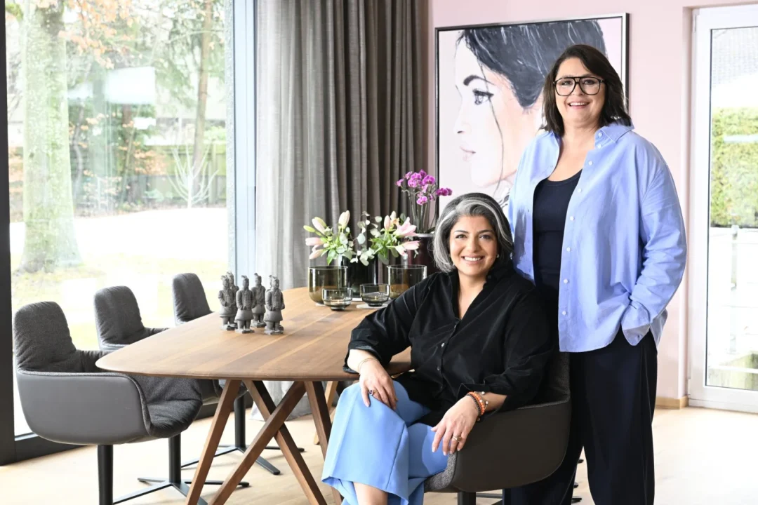 Sophia Lauton und Sahar Essmann im hellen Showroom mit Holztisch und grauen Sesseln