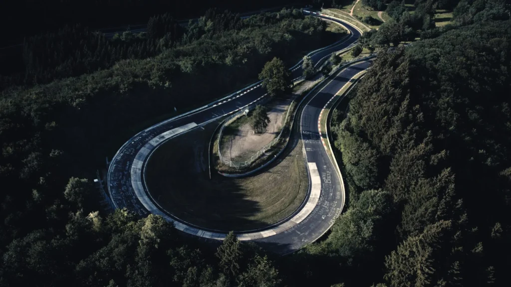 Luftaufnahme einer Kurvenkombination der Nürburgring-Nordschleife inmitten dichter Wälder