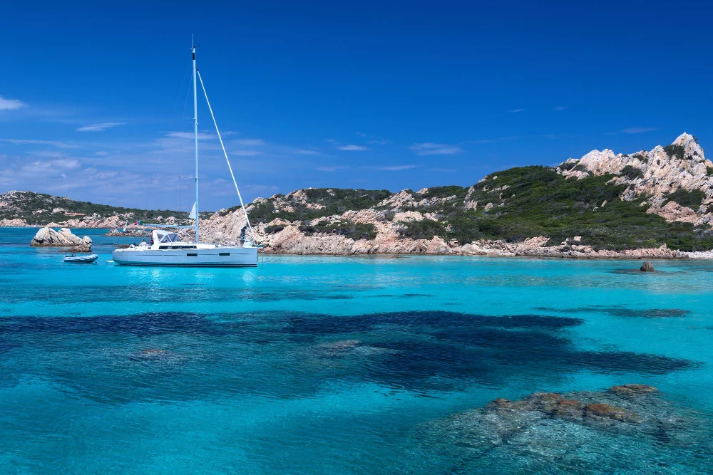 Segelyacht vor felsiger Mittelmeerküste in einer türkisblauen Bucht auf Mallorca