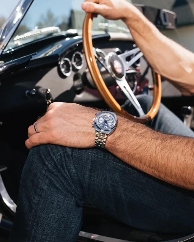 Bulova Shelby Racer Chronograph 96K118 am Handgelenk eines Fahrers in einem klassischen Sportwagen