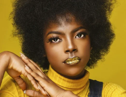 Beauty-Look mit goldglänzenden Lippen vor gelbem Hintergrund