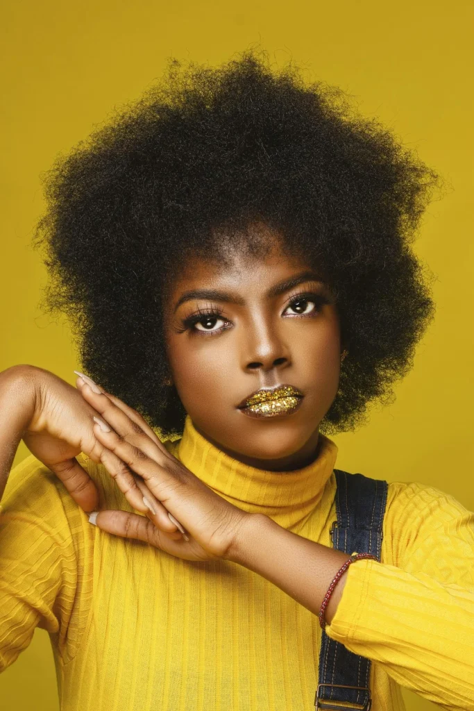 Beauty-Look mit goldglänzenden Lippen vor gelbem Hintergrund