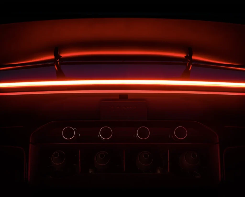 Tesla Roadster mit rot beleuchtetem Heck, durchgehendem LED-Rücklicht, großem Heckflügel und sichtbaren Düsen.