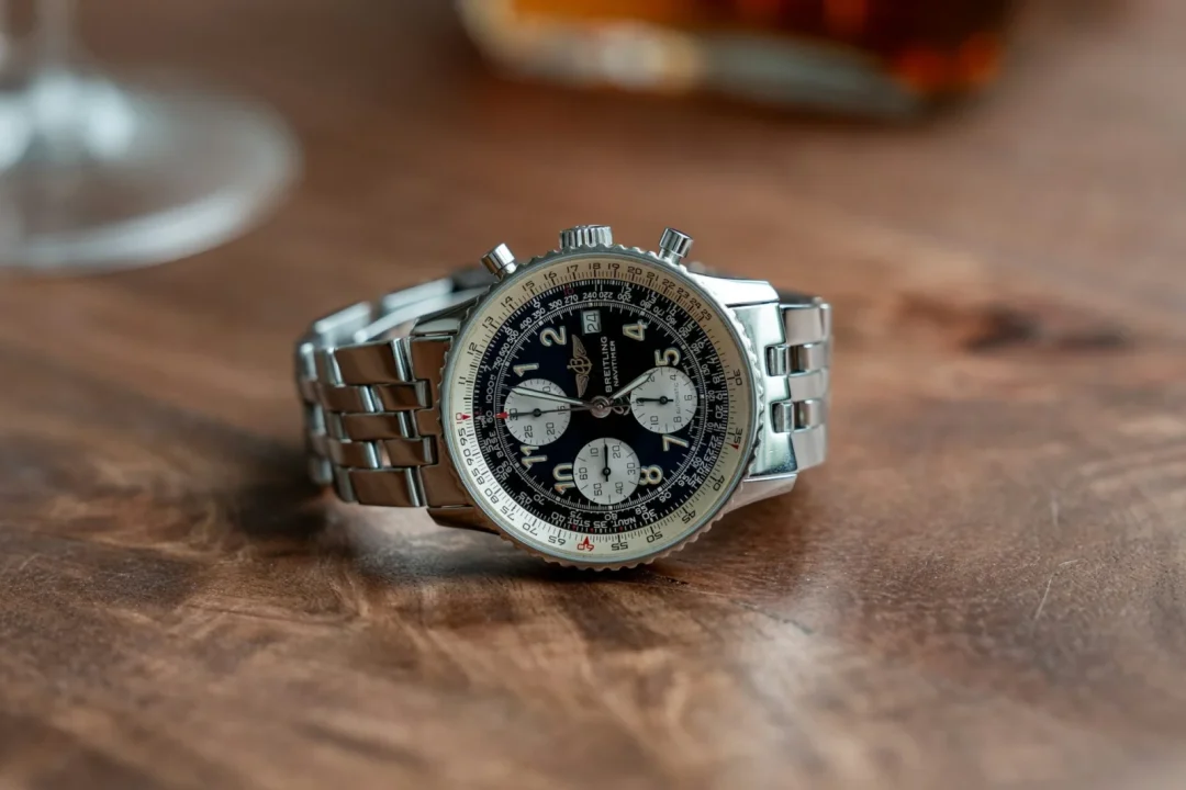 Breitling Navitimer Chronograph mit schwarzem Zifferblatt und Edelstahlarmband auf einem Holztisch